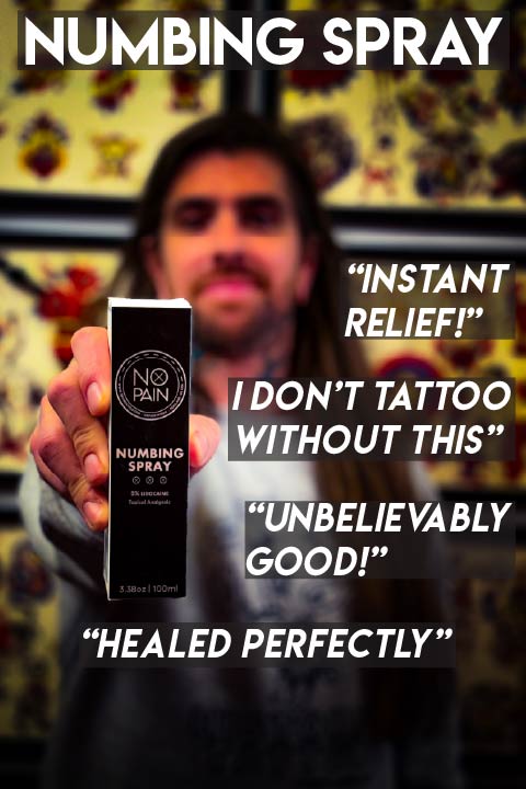Tattoo artist holding No Pain Tattoo Numbing Spray 3.38oz bottle in a tattoo shop with traditional flash — customer quotes: instant relief, unbelievably good, healed perfectly