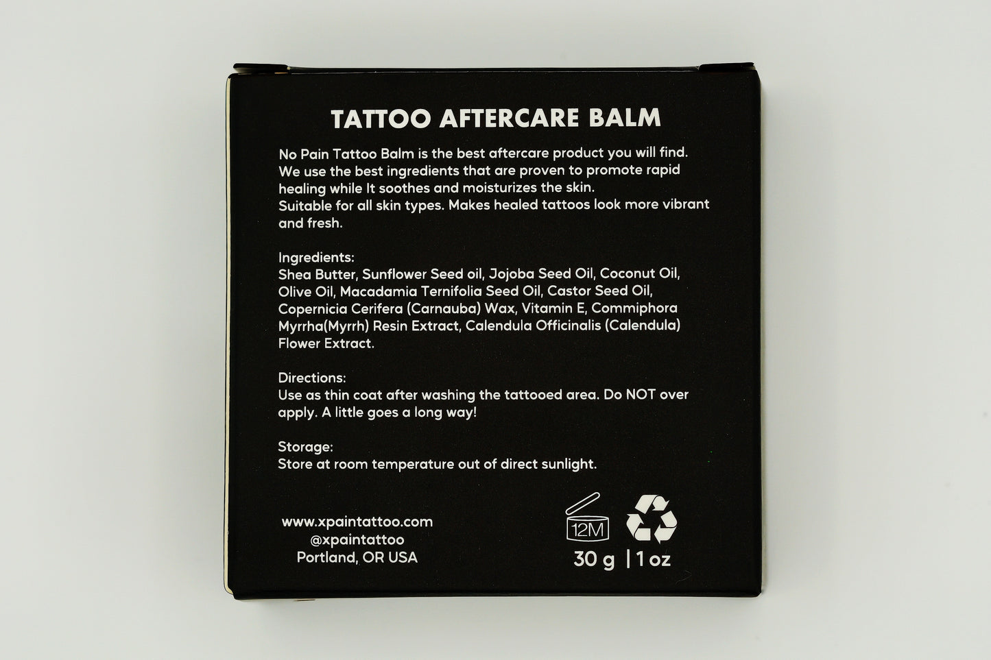 A square black container of "No Pain Tattoo Aftercare Balm 30g" from My Store is shown. The label lists ingredients, benefits, usage instructions, storage tips, and contact details for the manufacturer based in Portland, OR, USA. Designed to heal professional tattoos rapidly. The net weight is 30g (1oz).